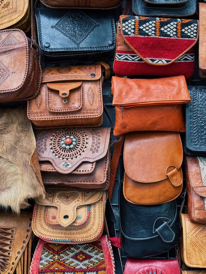 A diverse selection of handmade leather bags in various styles and colors on display.
